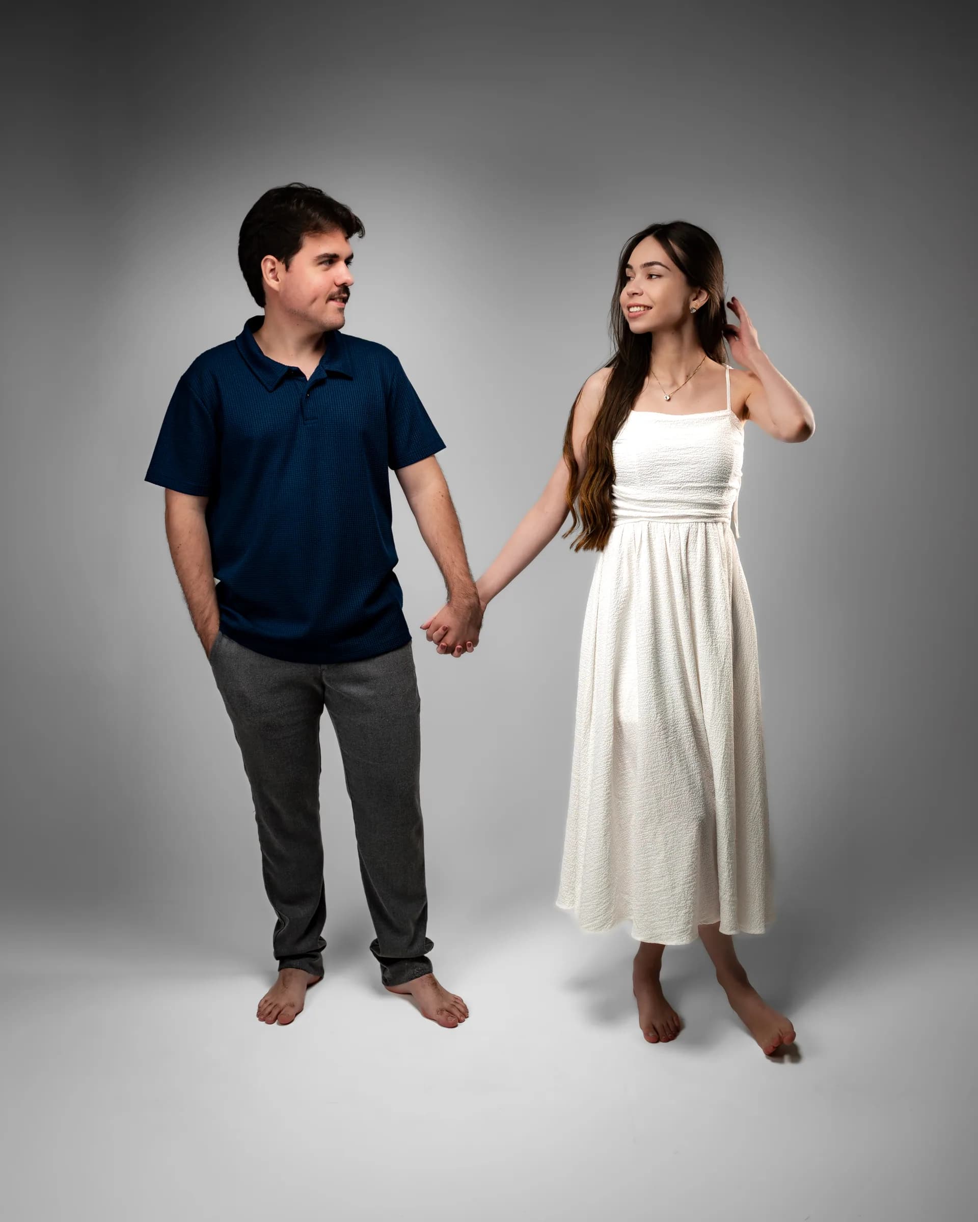 Casal descalço de mãos dadas, trocando olhares