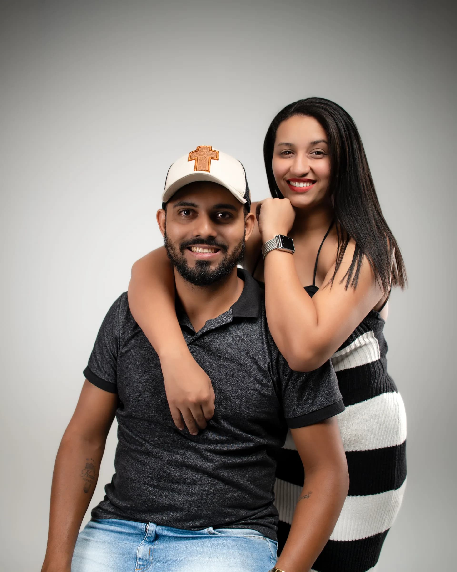 Ela abraçada às costas dele, os dois sorrindo para a câmera