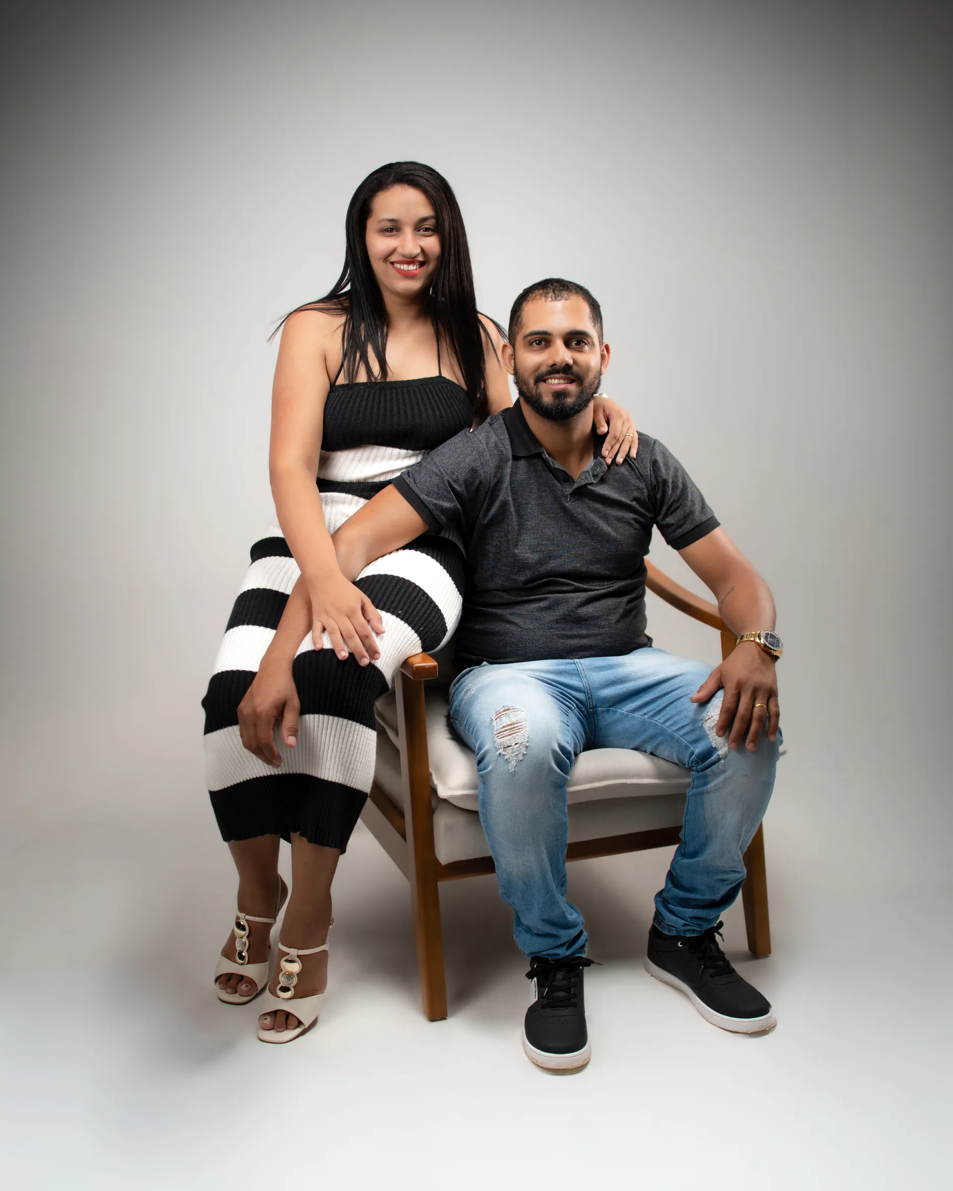 Casal na poltrona: ela sentada no braço, ele acomodado ao lado