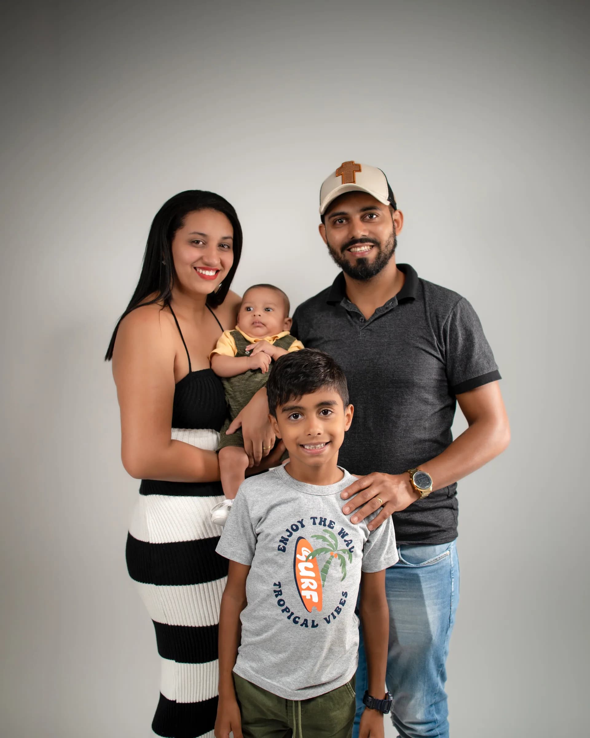 Família de quatro em pé, juntos, sorrindo para a câmera