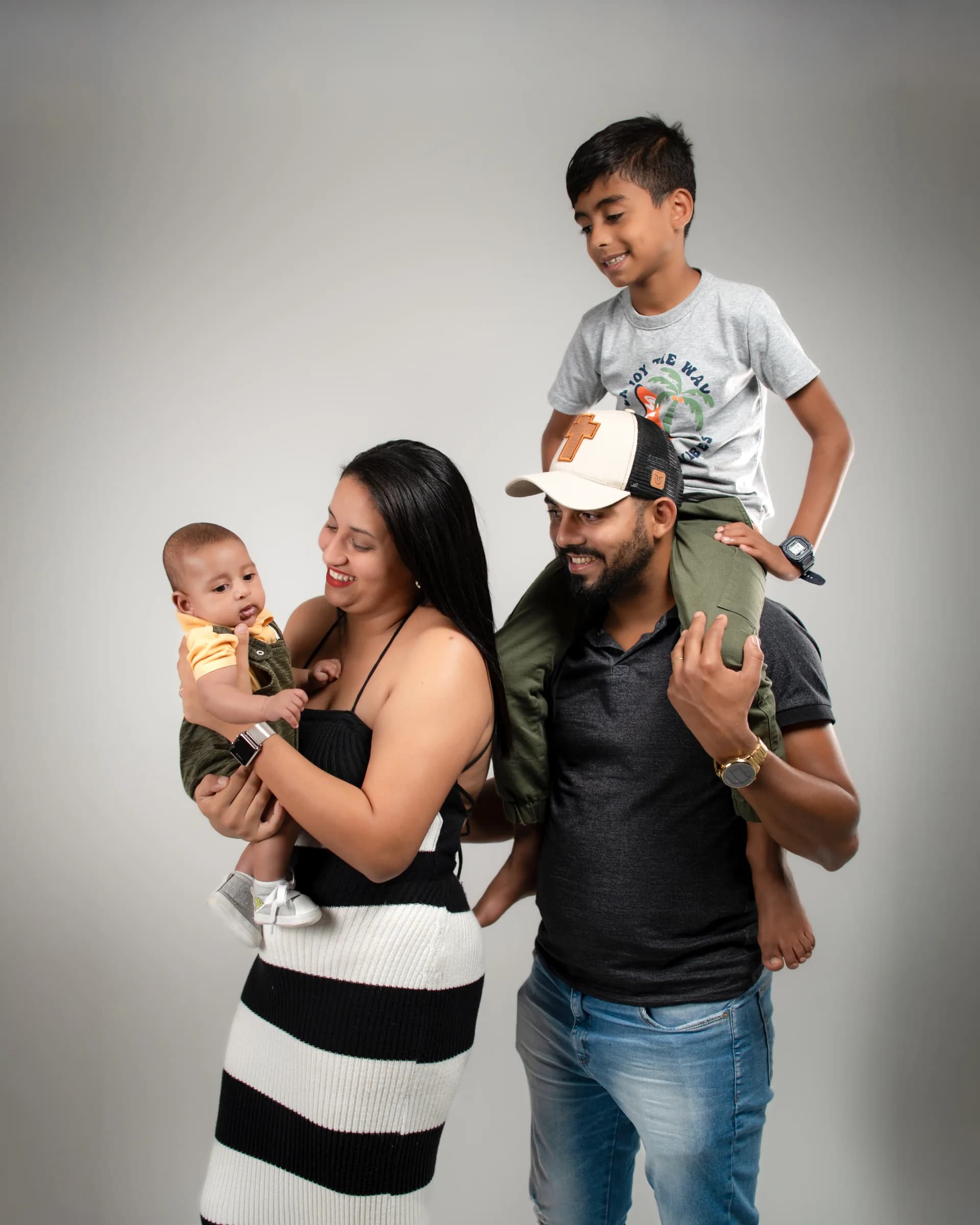 Mãe com o bebê no colo e pai com o filho mais velho nos ombros