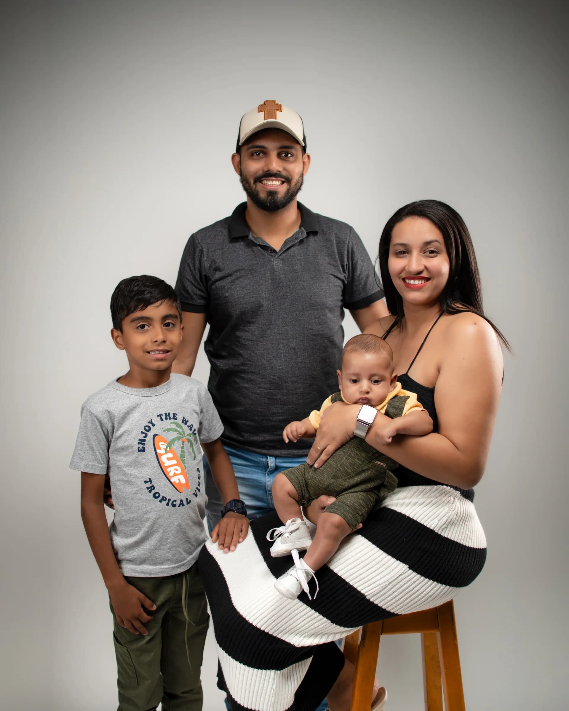 Pai ao centro, mãe sentada com o bebê no colo e o filho mais velho ao lado