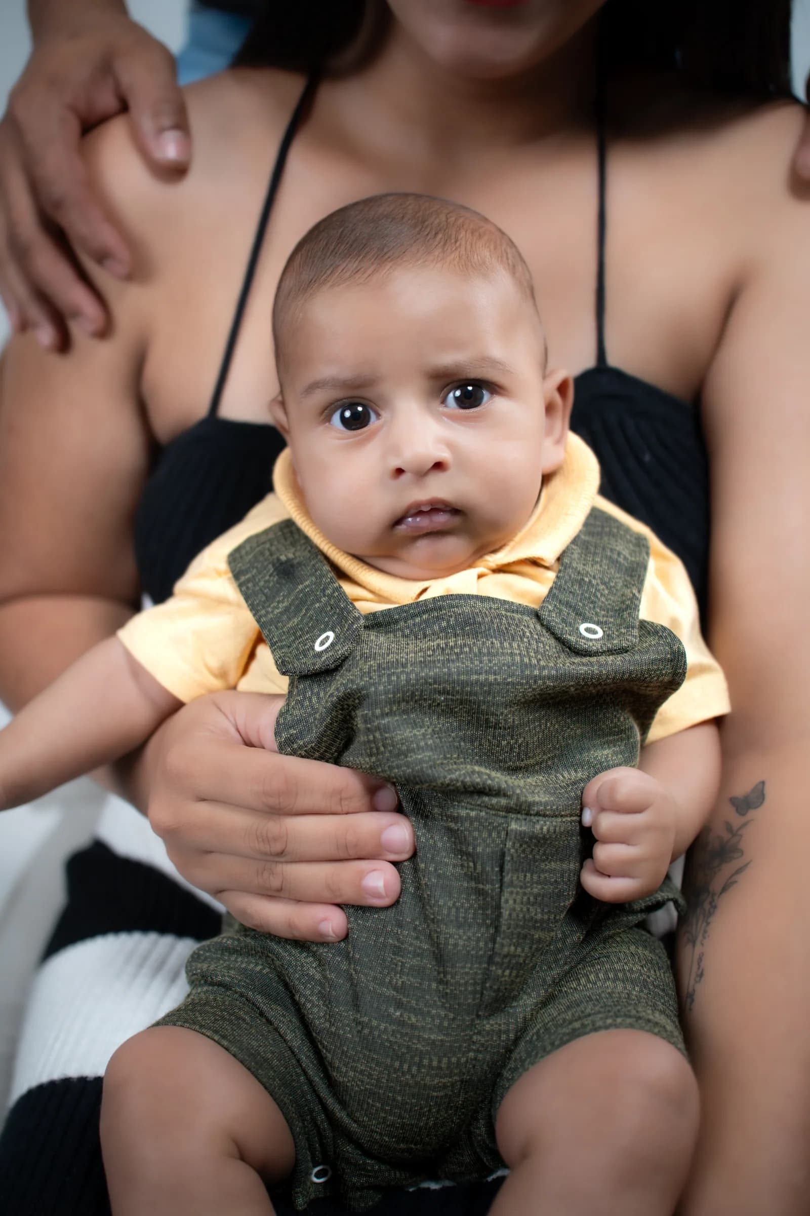 Retrato aproximado do bebê no colo da mãe, olhando para a câmera