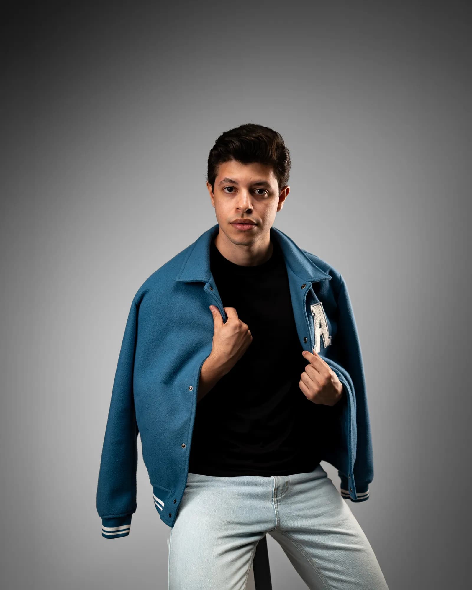 Jovem de camiseta preta sentado na poltrona, a mão apoiada no queixo