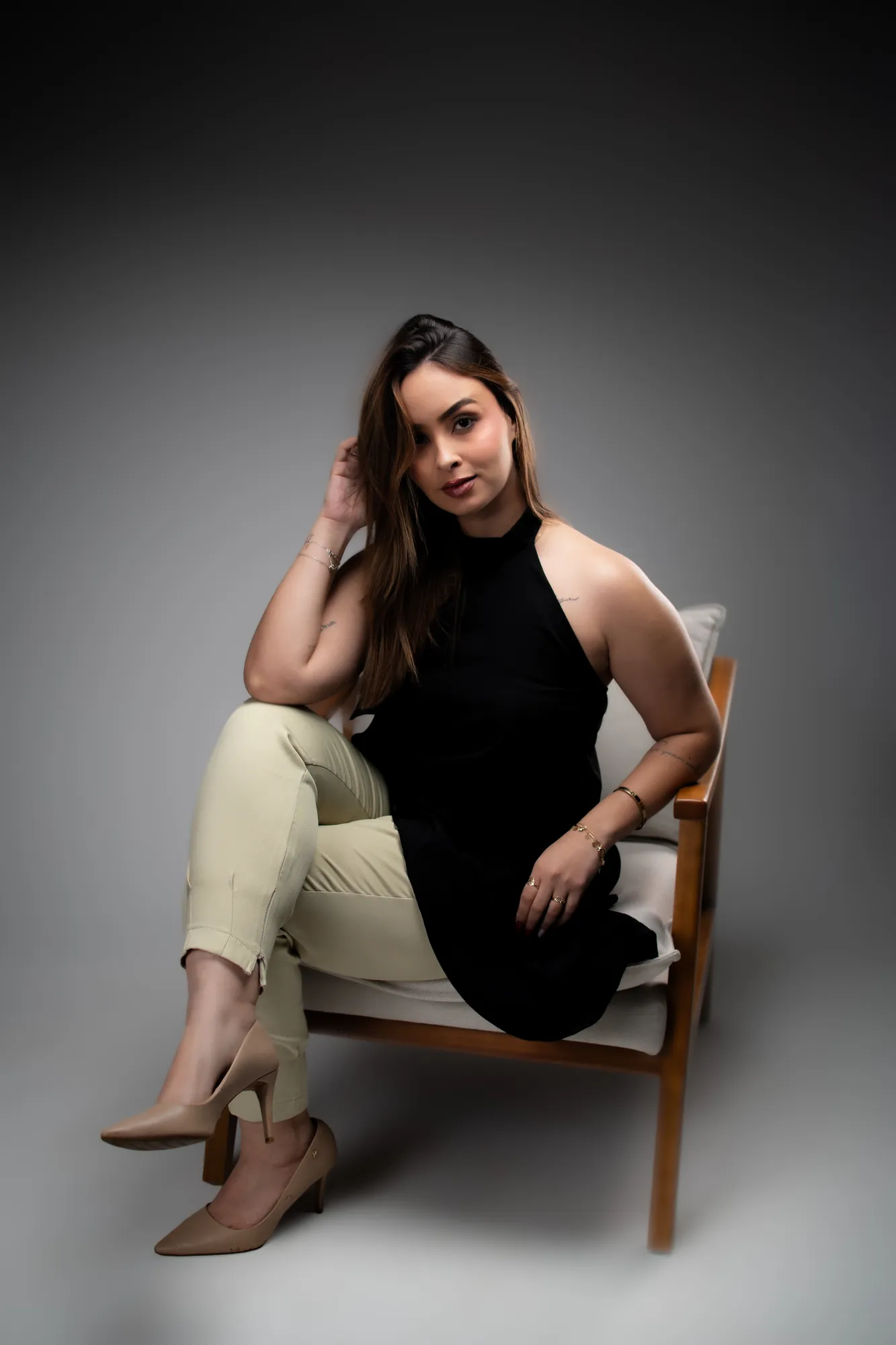 Mulher de blusa preta com a mão no queixo, em close de lado